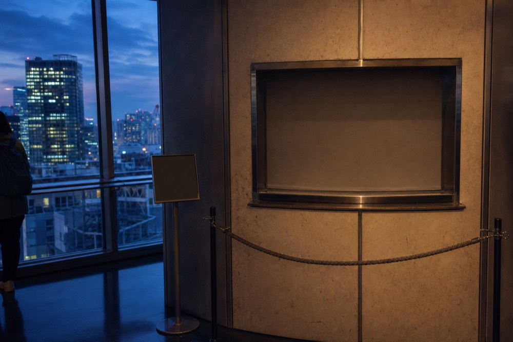 Empty walk up ticket window on an upper floor of a Tokyo tower with a rope barrier and a sign stand beside it