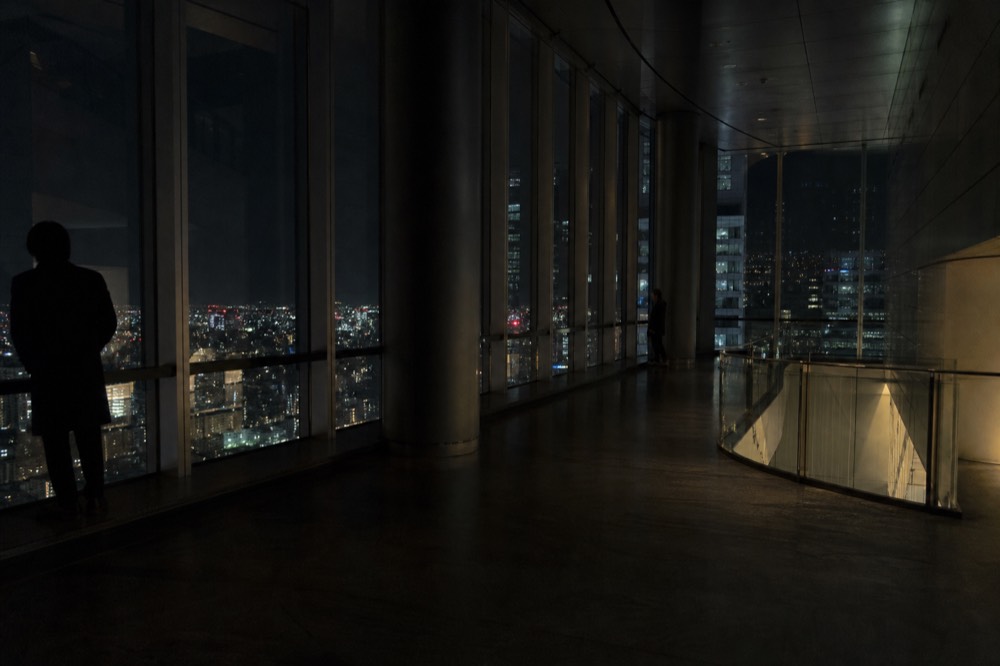 Empty high observation floor late at night with reflections on the glass and scattered city lights far below